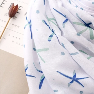 Detail shot of soft cotton linen scarf with blue starfish print and elegant fringe