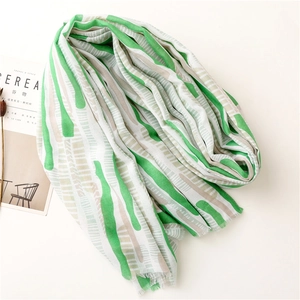 Detail of lightweight mint green striped scarf with fine frayed edges on a minimal background