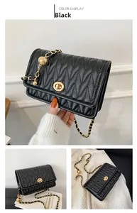 Detail of black quilted leather shoulder bag with gold chain strap and turn-lock closure