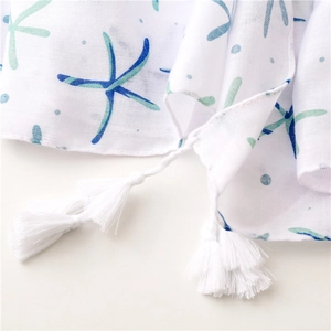 Close-up of white breathable scarf with blue starfish prints and soft cotton tassels
