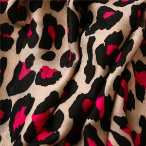 Macro shot of soft leopard print scarf fabric in rose red and black with elegant draping