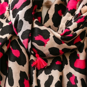 Macro view of woven leopard print fabric with decorative tassels and pink accents