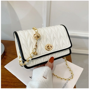 Detail of white quilted chain bag with gold ball accent and black contrast piping