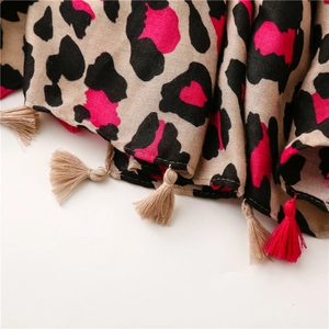 Detail of soft leopard print scarf with vibrant pink accents and braided fringe tassels