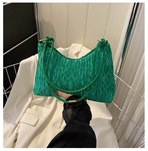 Close-up of green pleated shoulder bag with unique wavy texture and gold hardware detail