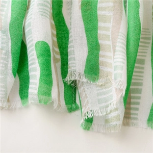 Detailed macro view of light green and white striped summer scarf with fringe edges