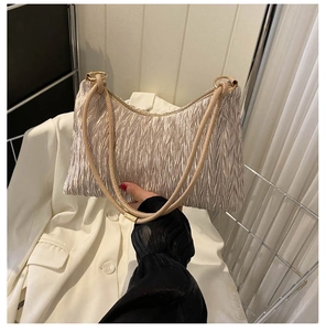 Detailed view of the pleated texture and metallic ring hardware on this beige underarm bag
