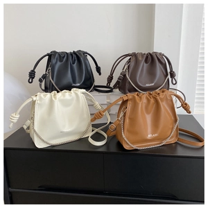 Dettaglio di eleganti borse a secchiello in quattro colori con coulisse e catena decorativa