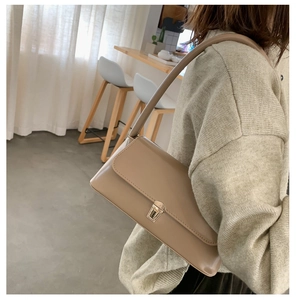 Detail of beige baguette bag showing the silver metal buckle and smooth leather texture
