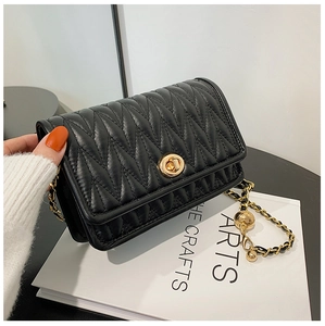 Detail of black quilted crossbody bag with golden chain strap and round metal buckle