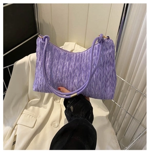 Close-up of a purple pleated underarm bag with metallic silk fabric and golden hardware