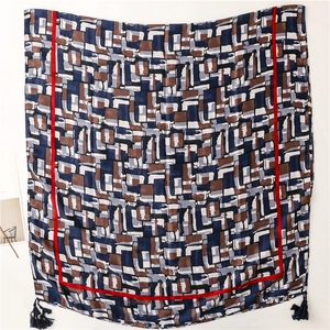 Detail of geometric pattern scarf with navy blocks, red borders and blue tassels