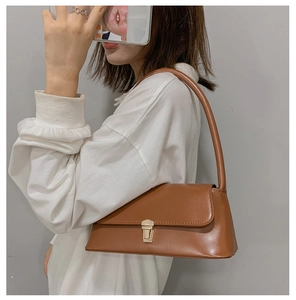Detail of matte brown leather baguette bag featuring a gold rectangular metal clasp lock