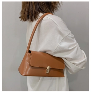 Detail view of brown vintage baguette bag with gold metal buckle on female model