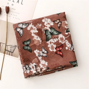 Gros plan d'une écharpe marron à motifs papillons et fleurs avec texture douce en lin