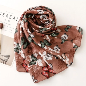Détail d'une écharpe marron caramel avec imprimé papillon et bords roulés fins