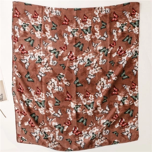 Détail d'une écharpe effet soie avec motifs papillons colorés et texture florale