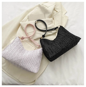 Detailed texture of pleated corduroy tote bags in lilac and black on a white blazer