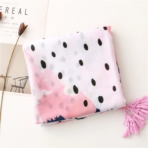 Détail d'une écharpe rose à pois avec de longs pompons et un tissu doux en coton et lin