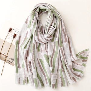 Detail of mint green summer shawl featuring abstract vertical patterns and fringed edges