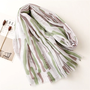 Close-up of mint green printed summer shawl with fringe edges and abstract patterns