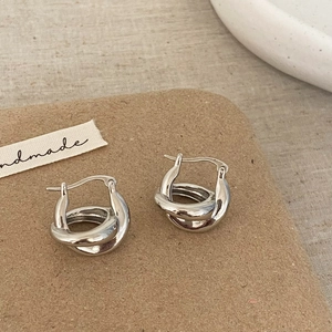 Gros plan détaillé de boucles d'oreilles torsadées en argent sur carte artisanale