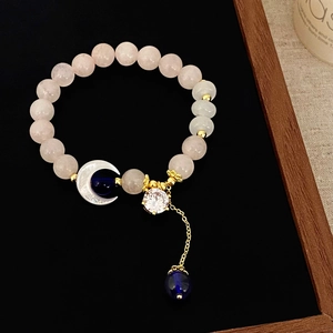 Pink quartz beaded bracelet with moon shell pendant and gold hardware on black background