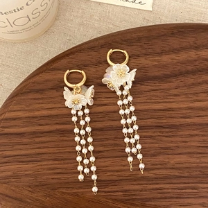 Detail of floral earrings with pearl tassels on a rustic wooden tray decoration