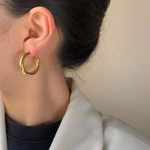 Elegante goldene Creolen für Damen mit Hochglanz-Finish, getragen von einem Model