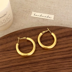 Elegante polierte dicke Gold-Creolen mit Spiegeleffekt auf rustikalem Holzuntergrund