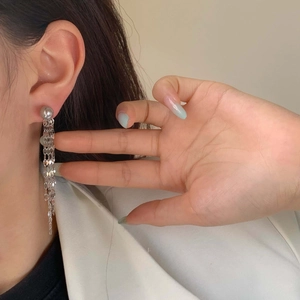 Elegant long silver tassel drop earrings with metal fringe chains worn by a model