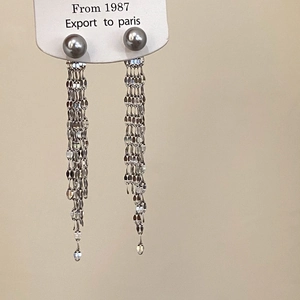 Detail of long tassel earrings featuring grey pearls and multiple silver metal chains