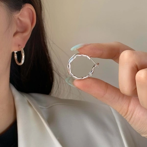 Minimalist silver irregular wave textured hoop earrings shown on a model for everyday style