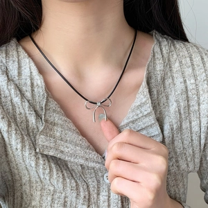 Elegant silver bow pendant necklace with black cord on model for a minimalist look