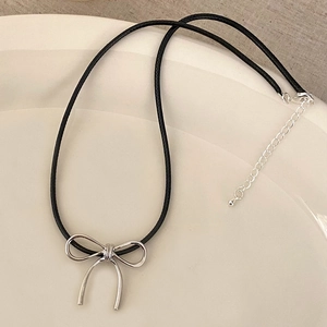 Detail of silver bow pendant on black cord necklace with adjustable extender chain