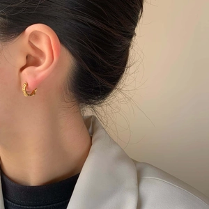 Vintage style gold hoop earrings with textured chain design worn by a female model