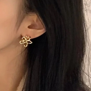 Detail of minimalist gold hollow flower earrings worn by a model for a daily elegant look