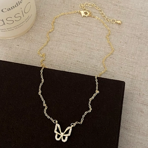 Detailed view of hollow butterfly pendant with white crystals and adjustable gold chain