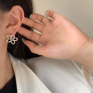 Close-up of elegant hollow flower stud earrings worn by a model for a minimalist style