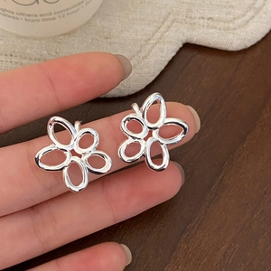 Detailed view of silver hollow flower stud earrings with a polished minimalist design