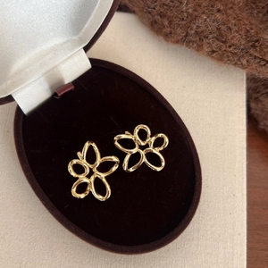 Detail of gold hollow flower stud earrings displayed in a premium velvet jewelry box