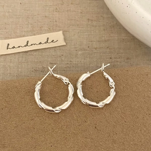 Detail of twisted rope texture silver metal hoop earrings on handmade card