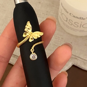 Macro detail of golden butterfly ring with sparkling zircon drop and textured metal wings
