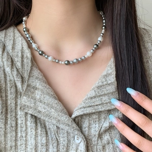 Elegant multi-tone pearl necklace featuring white and grey pearls on a striped sweater