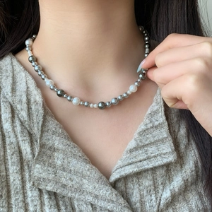 Elegant multi-color pearl necklace with white and grey pearls worn on a model
