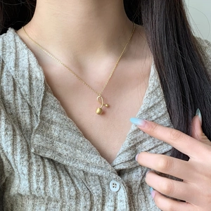Minimalist gold necklace with abstract curved pendant and frosted balls on a model