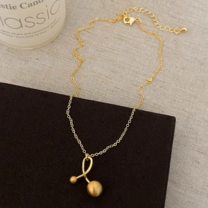 Detail of gold metal necklace with matte beads on a beige textured background