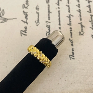 Close-up of golden braided texture ring with small zircon stones on vintage background