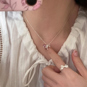 Detail shot of silver bow necklace and matching ring on model with lace collar