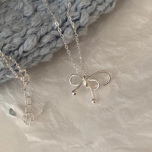 Detailed view of silver bow necklace with S925 sterling silver hallmark on the chain